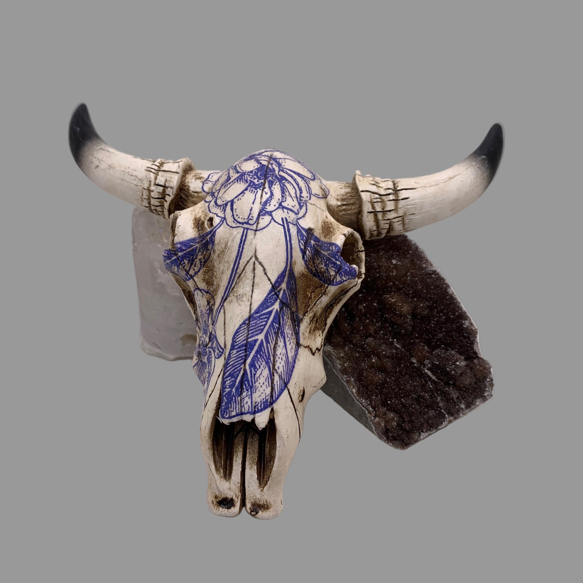 Decorative bull skull with blue floral design on a white background