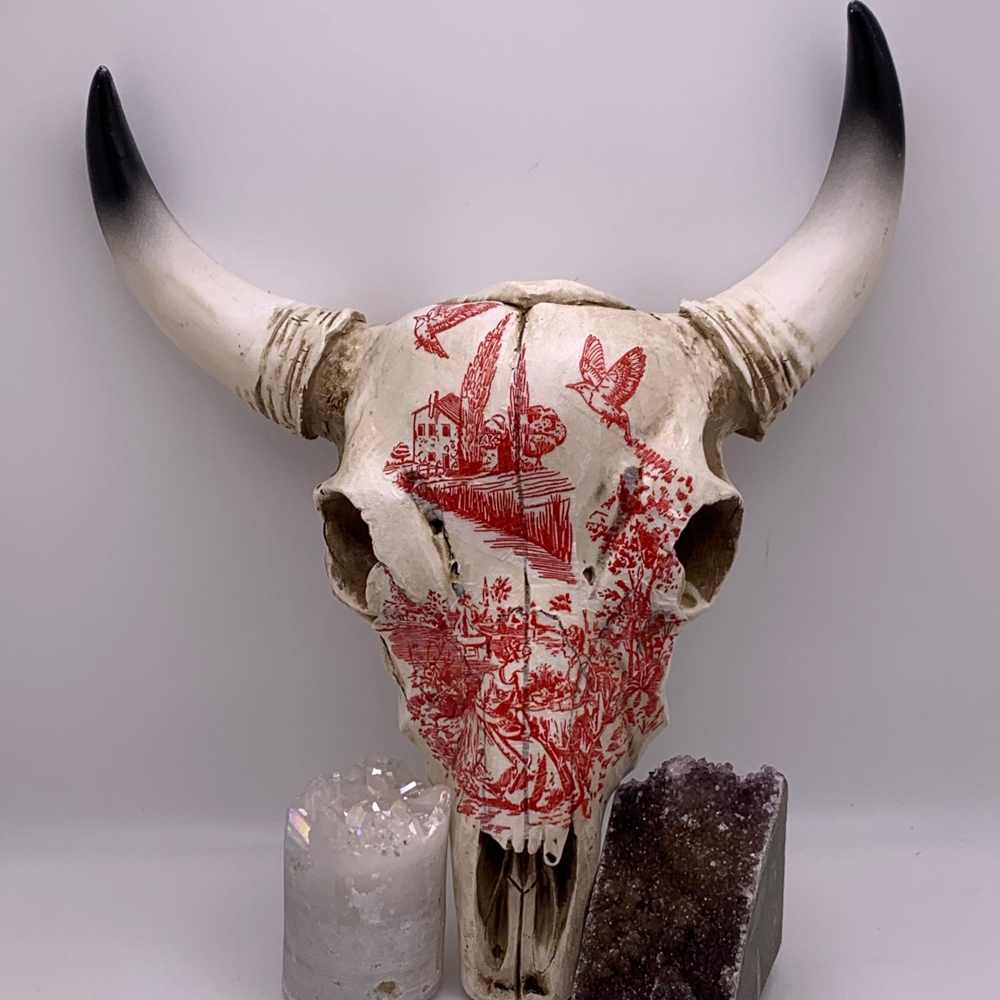 Decorative bull skull with red patterns, a crystal on a white background